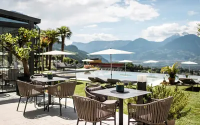 a patio with tables and chairs and a pool at Boutique Hotel Eschenlohe Adults only in Schenna