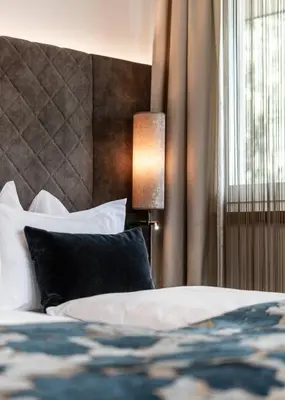a hotel room with a bed and a lamp at Boutique Hotel Eschenlohe Adults only in Schenna