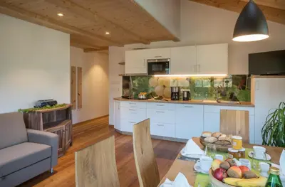 a kitchen with a wooden table and two chairs at Hofer Hof in Feldthurns