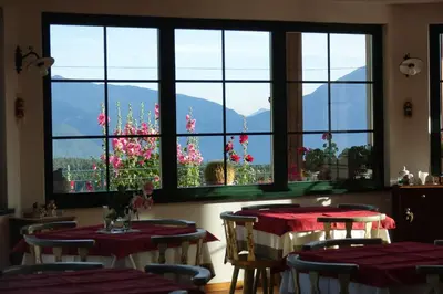a dining room with two tables and windows with flowers at La Capannina in Coredo