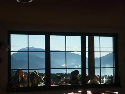 a group of people sitting at a table looking out a window at La Capannina in Coredo