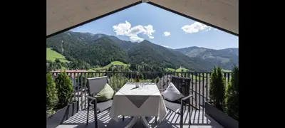 a table and chairs on a balcony with a view of mountains at Living Puez in Funes