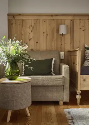 a living room with a couch and a table with a vase of flowers at Haus Tirol in Molini di Tures