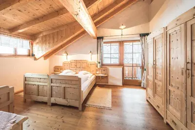a bedroom with a bed and wooden floors and windows at Haus Tirol in Molini di Tures