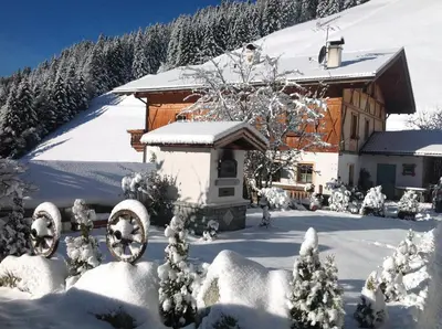 a house covered in snow in front of a house at Biohof Hamann in Sarntal