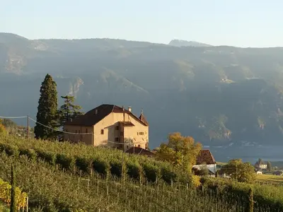 a church on a hill with a field of flowers at Schloss-Hof in Appiano sulla Strada del Vino