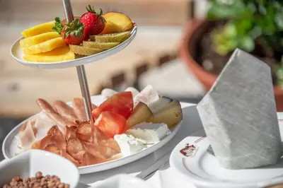 two plates of food sitting on a table with fruit at Hotel Bewaller in Obereggen