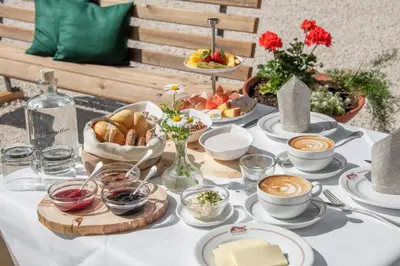 a table with a white table cloth with food and coffee at Hotel Bewaller in Obereggen