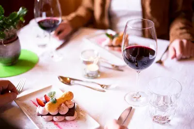 a table with two glasses of red wine and food at Almhotel Bergerhof in Sarntal