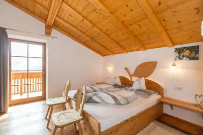 a bedroom with a bed with wooden ceilings and a window at Obergostnerhof in Chiusa