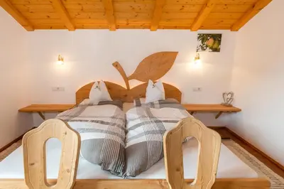 two beds in a room with two chairs at Obergostnerhof in Chiusa