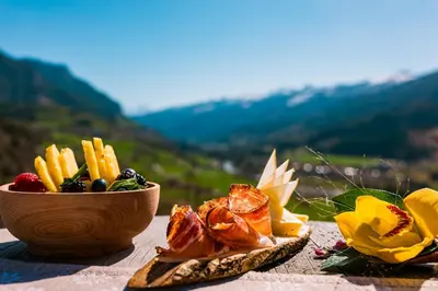 a table with a bowl of food and glasses of wine at La Roccia Wellness Hotel in Cavalese
