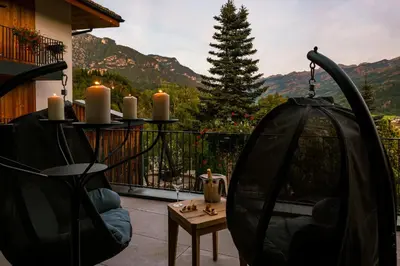 a room with two swing chairs on a patio at La Roccia Wellness Hotel in Cavalese