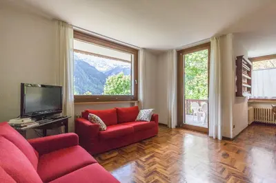 a living room with red furniture and a large window at Villa Licia in Falcade