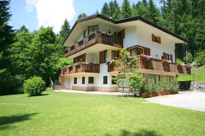 a large house with a balcony and a yard at Villa Licia in Falcade