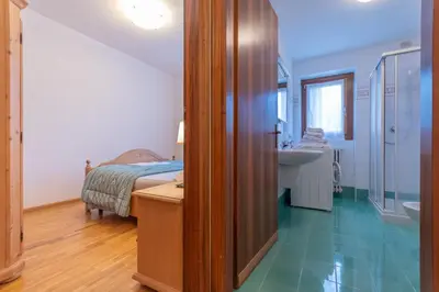 a bedroom with a bed and a bathroom with a sink at Villa Licia in Falcade