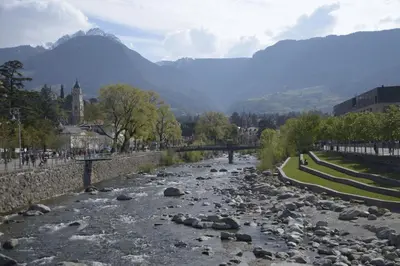 a river with rocks in a city with mountains at Appartment Trojer in Merano