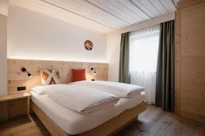 a bedroom with a large white bed and a window at CHALET MARLENE - Ferienhaus in San Vigilio Di Marebbe