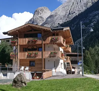a log building with a mountain in the background at Piccola Cesa Apartments in Canazei