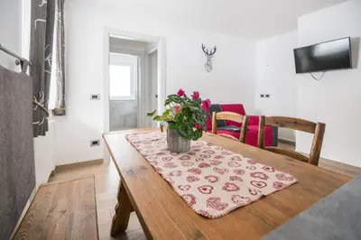 a dining room table with a vase of flowers on it at Piccola Cesa Apartments in Canazei