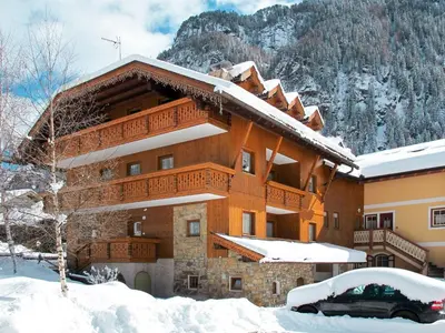 a building in the snow with a mountain in the background at Apartment Lazzer-2 by Interhome in Campitello