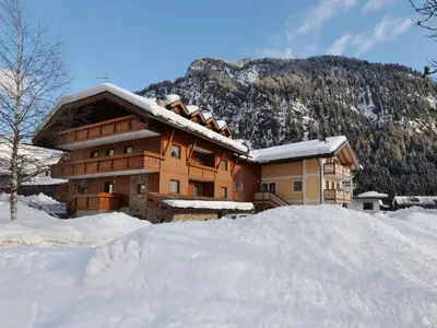 a building covered in snow with a car parked in front at Apartment Lazzer-2 by Interhome in Campitello