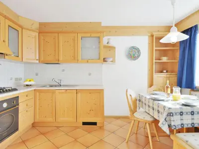 a kitchen with wooden cabinets and a stove top oven at Apartment Lazzer-2 by Interhome in Campitello