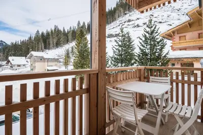 a wooden balcony with a table and chairs on it at Piccola Cesa B&B in Canazei