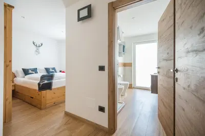 a bedroom with a bed and a door leading to a bathroom at Piccola Cesa B&B in Canazei