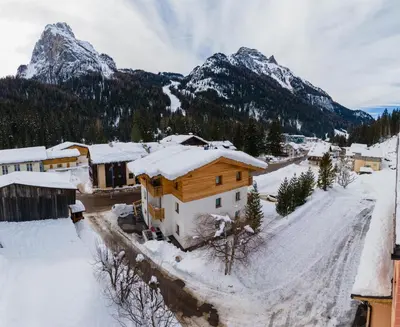 a snow covered village with mountains in the background at Piccola Cesa B&B in Canazei