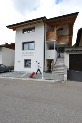 a man walking in front of a house with a suitcase at Ferienwohnung Haus Reider in Sarntal
