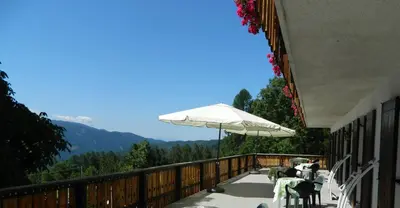 a balcony with an umbrella and tables and chairs at Hotel Ganzaie in Daiano