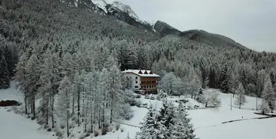 a building in the middle of a snow covered forest at Hotel Ganzaie in Daiano