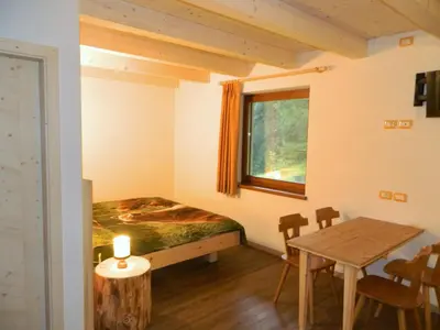 a bedroom with a bed and a table and a window at Hotel Ganzaie in Daiano