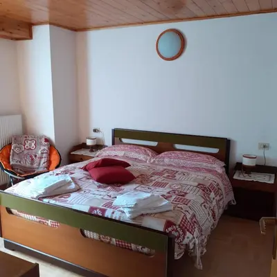 a bedroom with a bed with a red and white comforter at il Nido in Tonadico