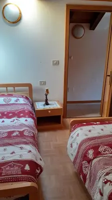 a bedroom with two beds and a table with a mirror at il Nido in Tonadico
