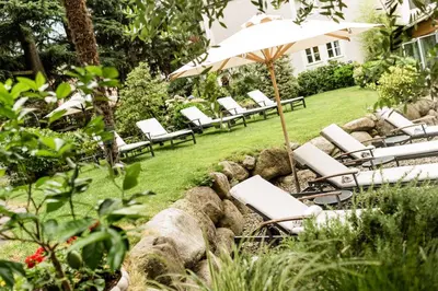 a group of chairs and an umbrella in a yard at Classic Hotel Meranerhof in Merano