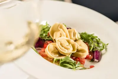 a white plate of food with pasta and vegetables at Classic Hotel Meranerhof in Merano
