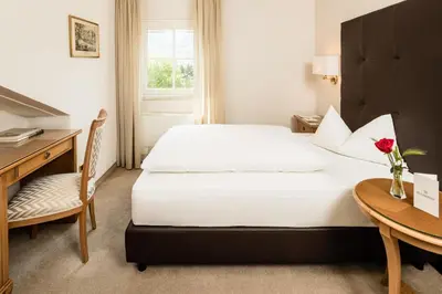 a hotel room with a bed and a desk and a table at Classic Hotel Meranerhof in Merano