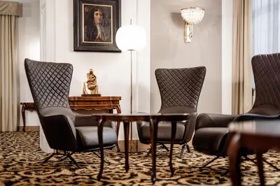 a room with chairs and a table and a lamp at Classic Hotel Meranerhof in Merano