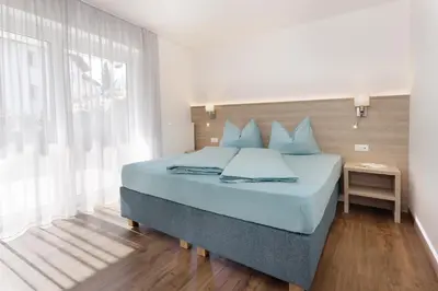 a bedroom with a bed with blue pillows and a window at Residence Apartment Nelkenstein in Schenna
