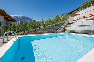 a swimming pool in front of a building at Residence Apartment Nelkenstein in Schenna