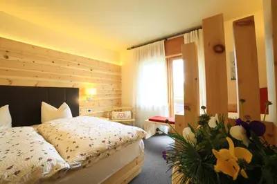 a bedroom with a bed and flowers in a room at Alpenhotel La Montanara in Rocca Pietore