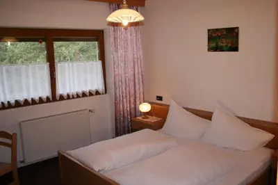 a bedroom with a bed with white sheets and a window at Gasthof Majestic in Bressanone