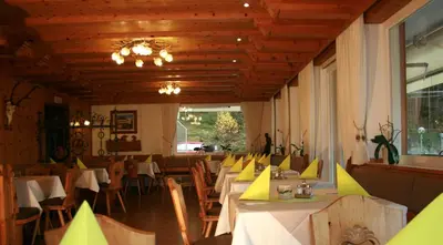 a dining room with tables and chairs and a chandelier at Gasthof Majestic in Bressanone