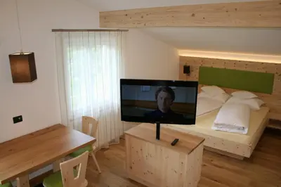 a living room with a television on a bed at Gasthof Majestic in Bressanone