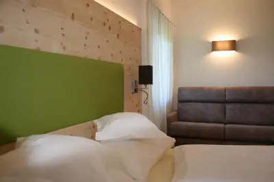a bedroom with two beds and a green wall at Gasthof Majestic in Bressanone