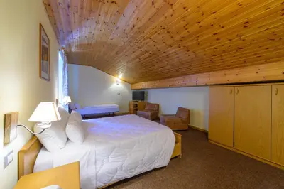 a bedroom with a white bed and a wooden ceiling at Park Hotel Faloria in Canazei