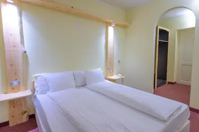 a large white bed in a room with a mirror at Park Hotel Faloria in Canazei