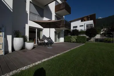 a house with a deck with a table and an umbrella at Residence Panorama in Brunico